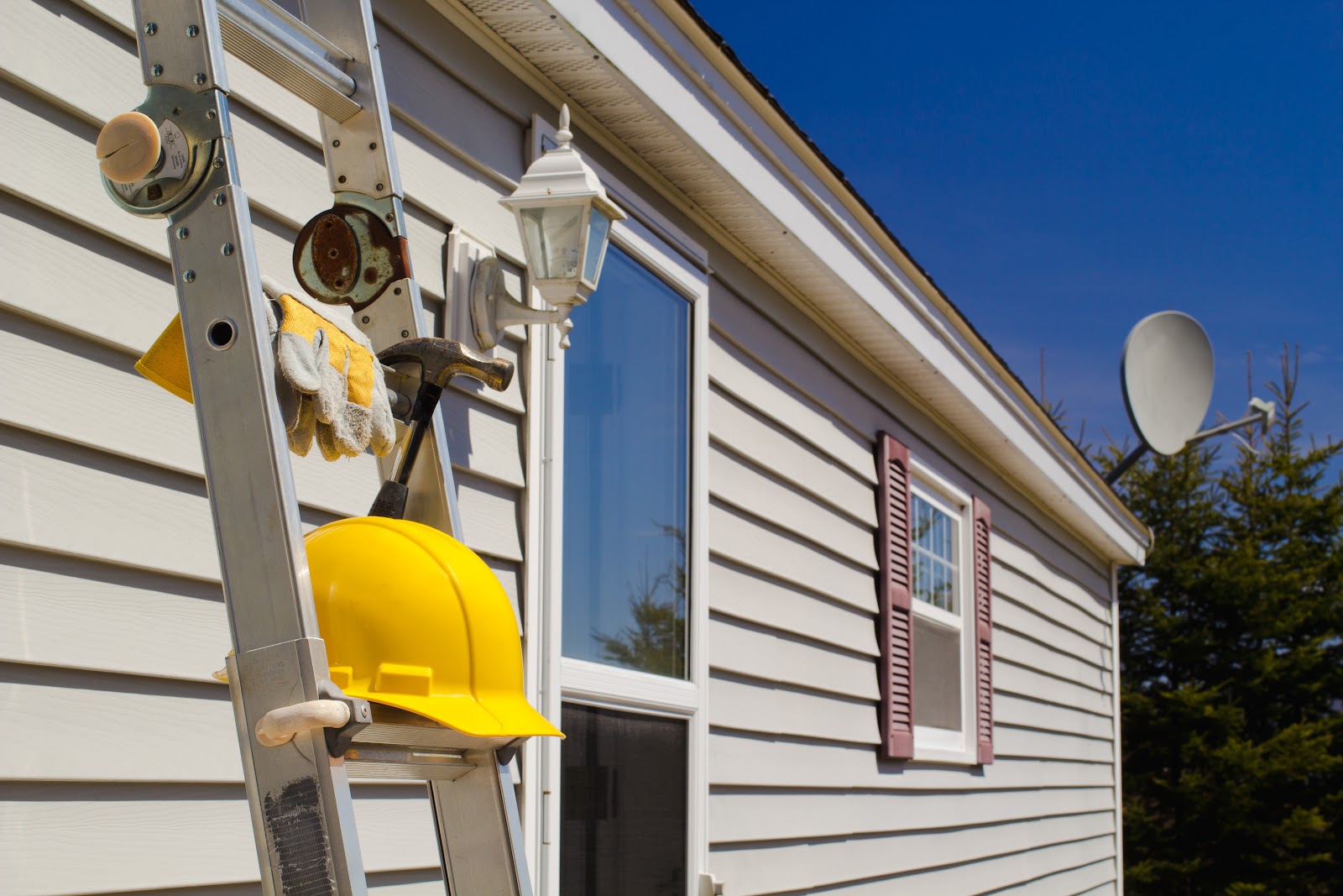 Ladder, hard hat, and tools against fresh siding on a Fort Wayne job site